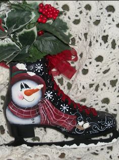 a snowman boot with holly leaves and red berries on the lace covered tablecloth