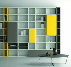 a modern living room with yellow and gray shelving units on the wall, including a coffee table