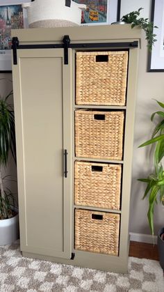 an armoire with wicker drawers and baskets on the bottom, next to a potted plant