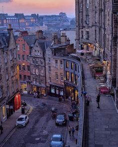 an aerial view of the city at dusk with cars parked on the street and buildings in the background