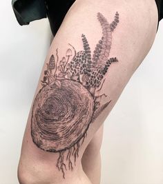 a woman's leg with a tree stump tattoo on her left thigh and flowers growing out of it