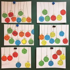 four pieces of paper with different colored balls hanging from it's sides on a green wall