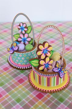 there are two small baskets with flowers in them on the checkered tablecloths