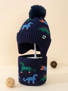 a blue hat with dinosaurs on it next to a ball