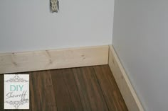 the corner of a room with wood flooring and a sign that says diy