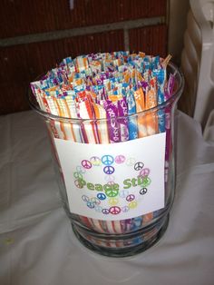 a glass bowl filled with candy sticks and peace signs on top of a white table cloth