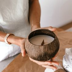 a woman holding a coconut bowl with a candle in it