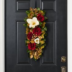 a black door with a red and white wreath hanging on it's front door