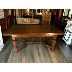 a large wooden table sitting on top of a hard wood floor next to a mirror