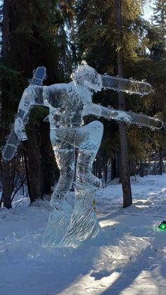 an ice sculpture in the snow with trees behind it