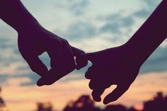 two hands holding each other with the sky in the background