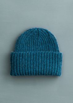 a blue knitted hat sitting on top of a white table next to a gray wall