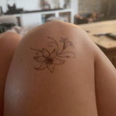 a woman's back with a flower tattoo on her left shoulder and the lower arm