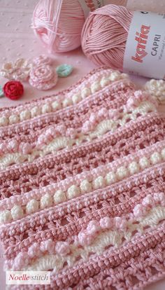 crocheted pink and white blanket next to balls of yarn