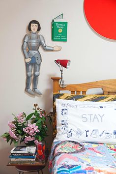 a bed room with a neatly made bed next to a wall mounted paper cutout