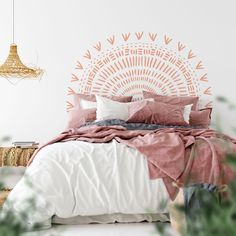 a bed with pillows and blankets on it in front of a wall hanging from the ceiling