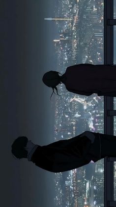 two people standing on top of a tall building looking out at the city lights and skyscrapers