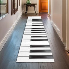 a long piano mat is on the floor in front of a door and table with a vase