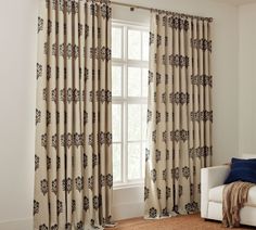 a living room with a white couch and two curtains on the window sill, in front of a large window