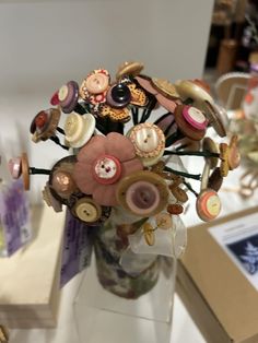 a vase filled with lots of buttons on top of a white table next to a box