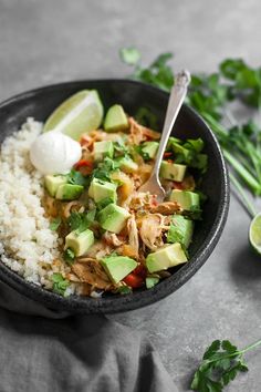 a black bowl filled with rice, avocado and other ingredients next to cilantro