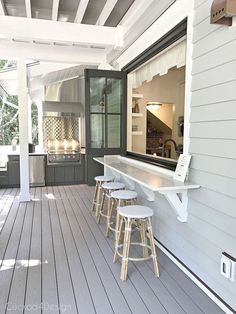 an outdoor kitchen with stools on the front porch