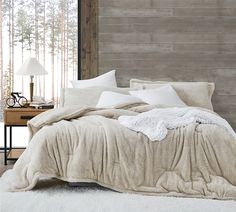 a bed with white sheets and pillows in a bedroom next to a wooden headboard