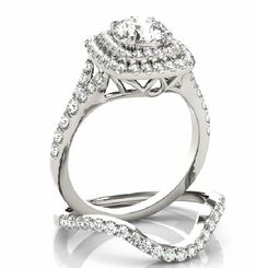 a white gold ring with two rows of diamonds on the band and an oval shaped center stone