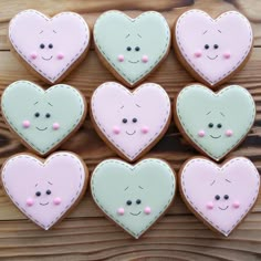 decorated cookies arranged in the shape of hearts on a wooden surface with pink and green accents