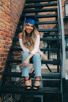 a woman sitting on top of a set of stairs wearing a graduation cap and jeans