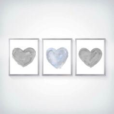 three framed art pieces with grey and white heart shapes on the wall in front of them