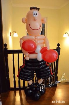 an inflatable balloon man sitting on top of a black chair with red balloons