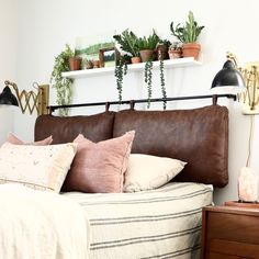 a bed with lots of pillows and plants on the headboard