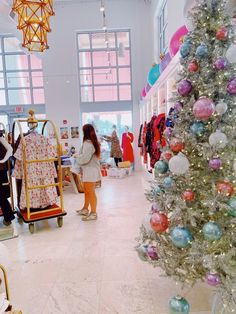 people are shopping in a store with christmas decorations on the walls and a large tree