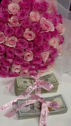 a bouquet of pink roses sitting on top of money