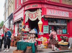 people are standing outside an antique shop on the street corner in front of red building