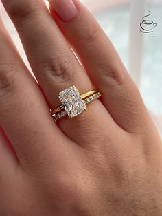 a woman's hand with a diamond ring on top of her finger and an engagement band