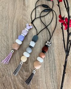 four different necklaces with tassels and beads hanging from them on a wooden table