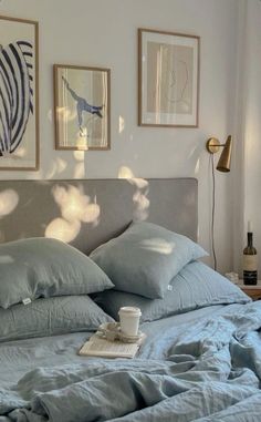 a bed with blue sheets, pillows and pictures on the wall