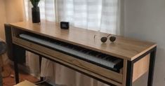 a piano sitting in front of a window next to a vase with flowers on it