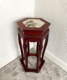 a small wooden table sitting on top of a carpeted floor next to a white wall