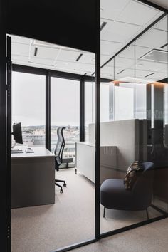 an office with glass walls and black chairs in the foreground, looking out onto a cityscape