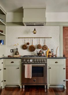 a stove top oven sitting inside of a kitchen next to wooden flooring and cabinets