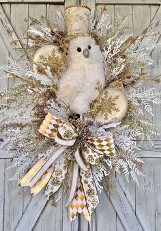 a wreath with a white teddy bear wearing a top hat and gold bow on the front door