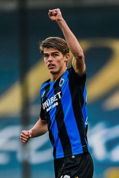 a young man is playing soccer and raising his arm in the air with one hand up