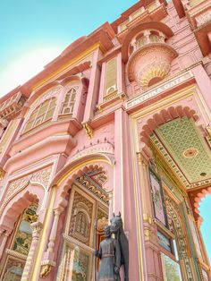 an ornate pink building with statues on the front