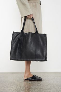 The Large Grocer Leather Tote in grain black is inspired by the familiar supermarket shopper bag. Worn as a shoulder bag with a comfortable drop length, this grocer bag blends a familiar generic mood with a high-quality finish suited for use as a work bag, travel bag or effortless everyday bag. Handcrafted from the finest Italian soft pebble grain aniline leather in our Melbourne Atelier. Delivered in an exclusive A-ESQUE cotton drawstring dust bag for preservation and luxury. Rectangular Textured Leather Hobo Bag For Shopping, Minimalist Black Shoulder Bag With Smooth Grain, Black Smooth Grain Hobo Bag For Business, Black Smooth Grain Hobo Bag For Daily Use, Black Smooth Grain Hobo Bag For Everyday, Black Textured Leather Rectangular Hobo Bag, Black Smooth Grain Hobo Bag, Black Rectangular Textured Leather Hobo Bag, Black Smooth Grain Shoulder Bag For Work