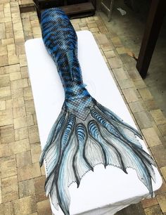 a blue and white mermaid tail is on a bed with a sheet that has been drawn onto it