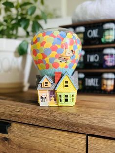 a toy hot air balloon sitting on top of a wooden table next to some books