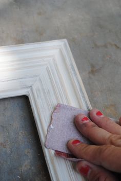 a person holding a piece of paper in front of a white frame on the ground